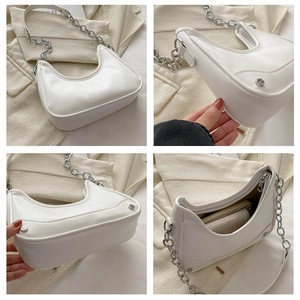Detail view of white half-moon underarm bag with silver chain and rivet accents