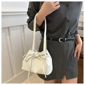 Dettaglio di una borsa a secchiello bianca con cordoncino decorativo a fiocco