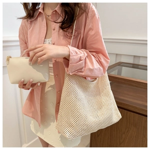Détail du sac cabas tissé ajouré et sa pochette zippée portés avec une tenue d'été