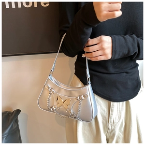 Detalle del bolso hobo plateado metalizado con un gran adorno de mariposa dorada y remaches