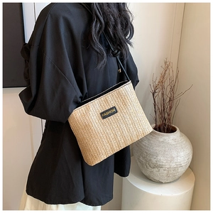 Detail shot of hand-woven crossbody bag with black leather strap and fashion label