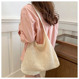 Detail of cream hollow-out woven tote bag with wide shoulder strap on a female model