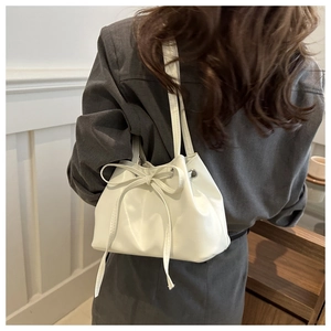 Chic cream white bucket bag with bow drawstring detail worn by model for office commuting