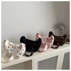 Detailed row of strawberry embroidered corduroy hobo bags in four different colors