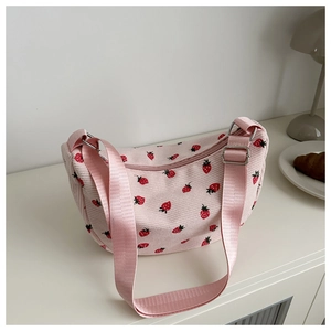 Detail of pink corduroy shoulder bag with red strawberry print and adjustable strap