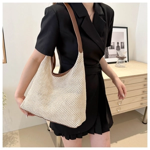Detail of hand-woven mesh tote bag with brown leather handles in minimalist interior