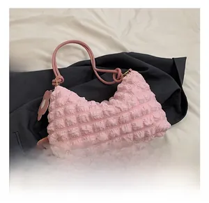Detail of pink popcorn texture nylon shoulder bag with floral charm on blue blazer