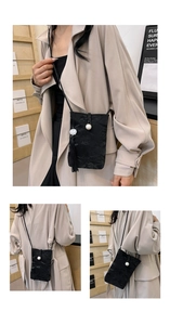 Detail of black crossbody bag with textured finish, large pearl and flowing tassel detail