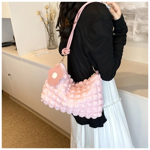 Detail of pink bubble texture fabric on underarm bag with flower charm and knot strap