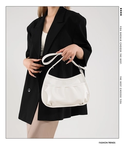 Detail of white pleated soft PU leather crescent bag shown on model for daily styling