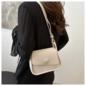 Detailed texture of ivory lychee pattern leather saddle bag shown on model