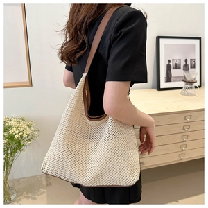 Detailed texture of hand-woven beige straw tote bag with brown leather shoulder straps