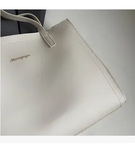 Macro detail of creamy leather tote bag showing fine texture and golden logo