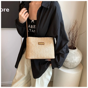 Detail of beige straw bucket bag with fashion label on a stylish model outfit