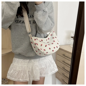 Detail of strawberry embroidery on cream corduroy half-moon crossbody bag with strap