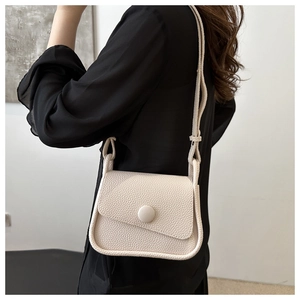 Detail of lychee textured saddle bag featuring a knotted strap and matching round button
