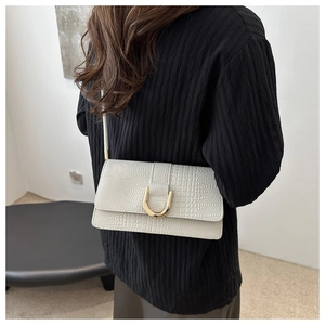 Détail d'un sac à bandoulière blanc motif crocodile avec boucle en U en métal doré