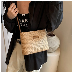 Dettaglio borsa tote in paglia con etichetta in pelle marrone e trama intrecciata