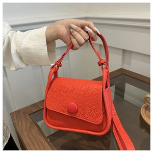 Detail of vibrant orange litchi grain saddle bag with stylish round buckle closure