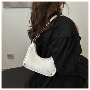 Close-up of white crescent bag with silver chain strap and metal rivet details