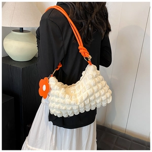 Detail of white popcorn texture tote bag with orange rope strap and flower charm