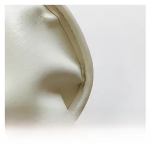 Detail shot of premium cream-colored faux leather texture and precise edge stitching