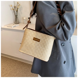 Detail of a straw bucket bag with leather 'FASHION' patch and crossbody rope strap
