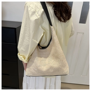 Detail of beige mesh crochet shoulder bag featuring broad black straps and airy triangle shape