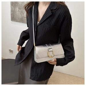 Détail du sac bandoulière argenté métallisé avec texture croco et boucle dorée sur modèle