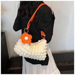 Detail of white popcorn textured shoulder bag with orange handle and flower charm