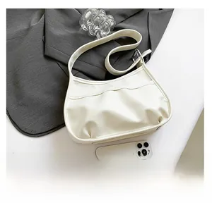 Top view of a beige leather saddle bag with pleated front pockets on a white surface