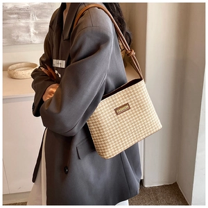 Detail of hand-woven straw bucket bag featuring a brown leather strap and FASHION tag
