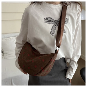Detail of brown corduroy saddle bag featuring cute strawberry embroidery and adjustable strap