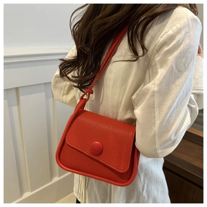 Detail of red lychee textured leather crossbody bag with a large round button closure