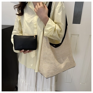 Détail du sac cabas en paille tissée avec anses noires et pochette zippée assortie
