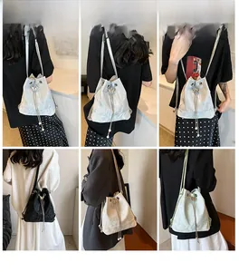 Detail of drawstring bucket bag featuring a metal butterfly buckle and pearl tassel accents