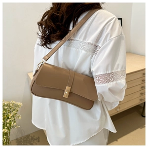 Détail d'un sac baguette en cuir marron avec un fermoir rotatif en métal doré élégant