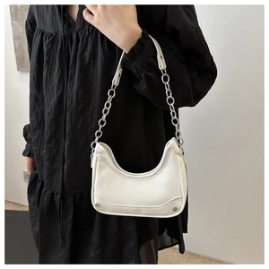 Detail of white leather crescent underarm bag with silver chain strap on model