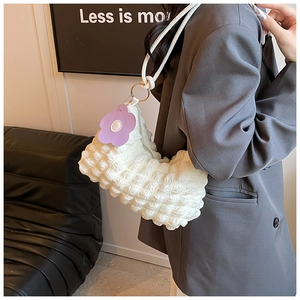 Close-up of beige ruched cloud bag featuring unique bubble texture and floral pendant