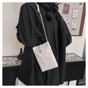 Elegante gebroken witte crossbody telefoontas met grote parelgesp en geweven riem