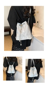 Detail of silver pleated drawstring bucket backpack with butterfly buckle and pearls