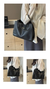 Detail of large black tote bag featuring white contrast stitching and gold logo