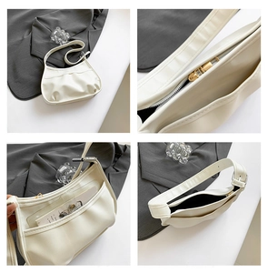 Detail view of cream white crescent shoulder bag featuring front pocket and adjustable strap