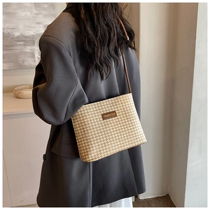 Detail of woven straw bucket bag with checkerboard pattern and fashion leather patch