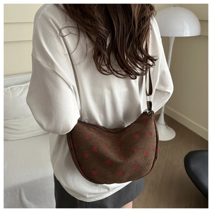 Detail of vintage brown corduroy crescent bag with red strawberry patterns and wide strap