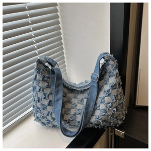 Gros plan du sac bandoulière en denim à damier bleu avec détails de franges texturées