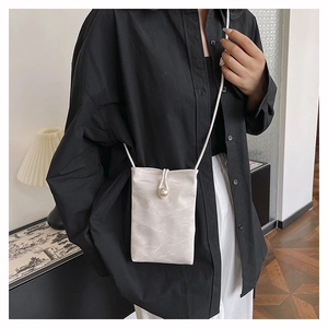 Detail van witte mini crossbody tas met marmeren textuur en grote parelsluiting