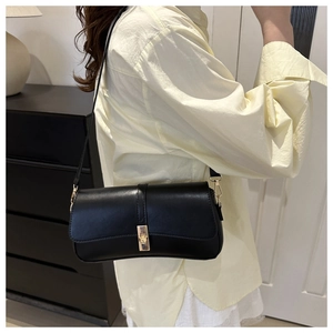 Détail du sac à bandoulière en similicuir noir avec un fermoir rotatif en métal doré