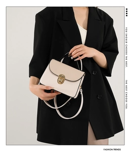 Detail of elegant two-tone square bag with gold twist lock and fine shoulder strap