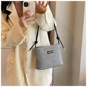 Detail of fashion houndstooth crossbody bucket bag with rope strap and metal tips